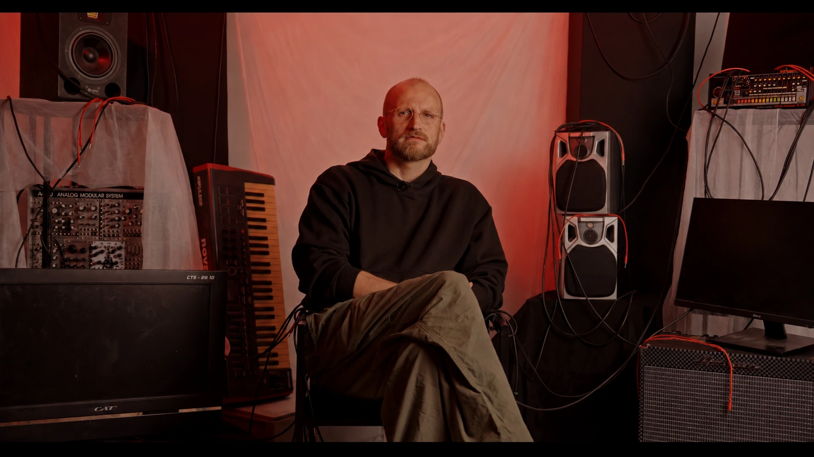 Musician seated by studio monitors, Behind the Concrete Wall