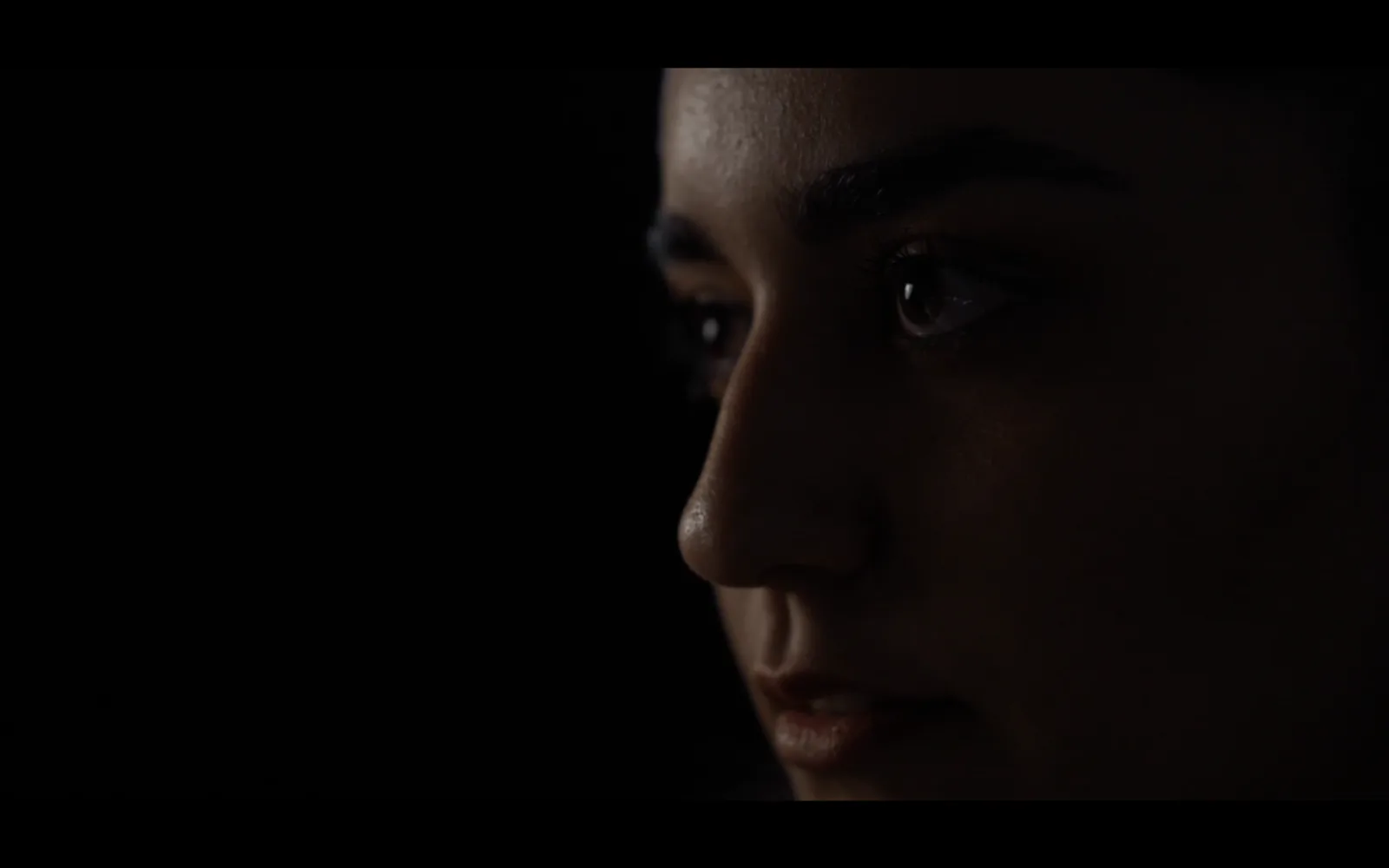 Cinematography still from Bride of Stolen, a face by candlelight in deep shadow